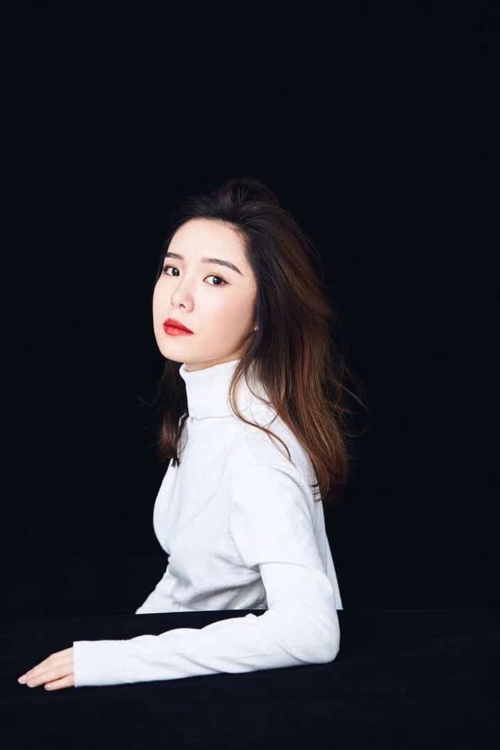 Amelia in a white skivvy, pictured in an all-black background.
