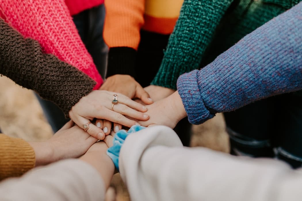 A photograph of many hands in the center together, collected one on top of each other.