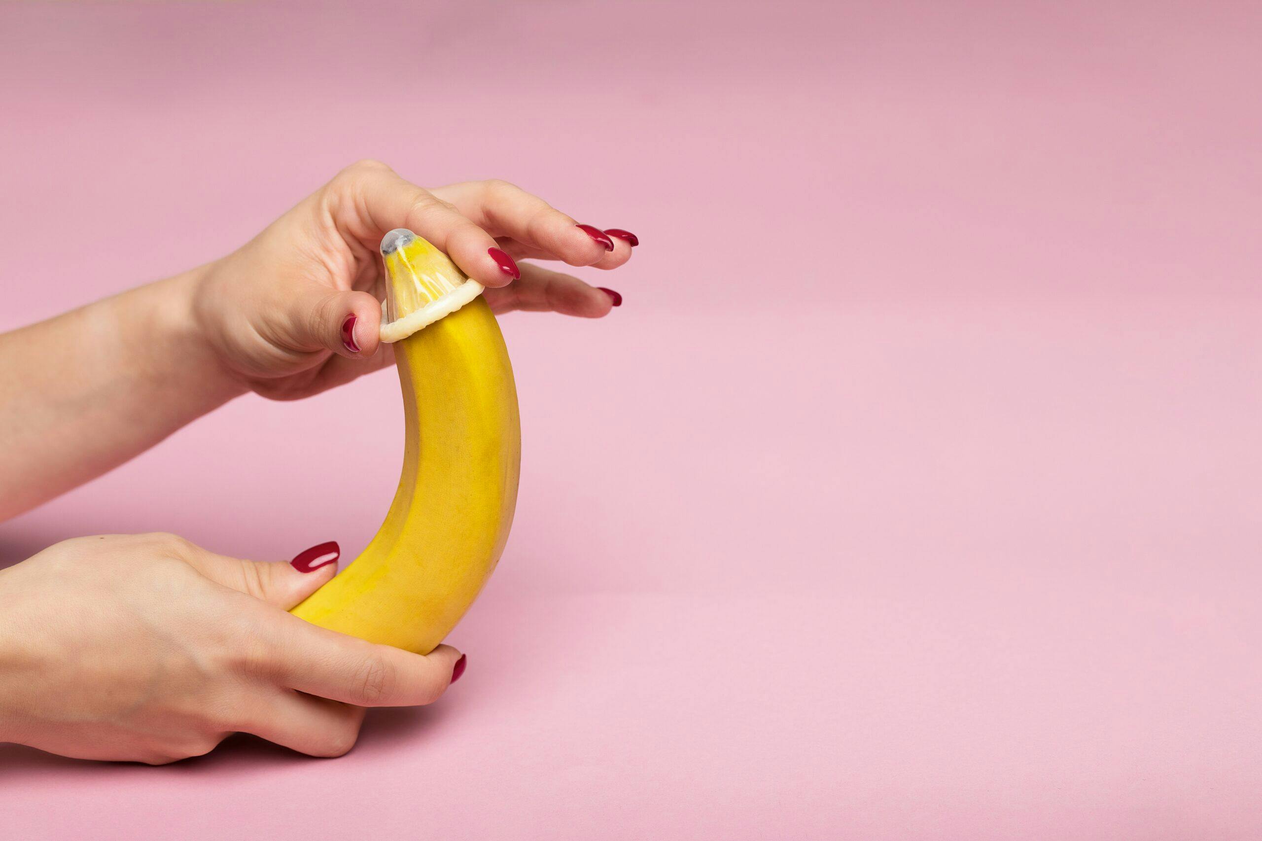 Someone putting a condom on a banana.
