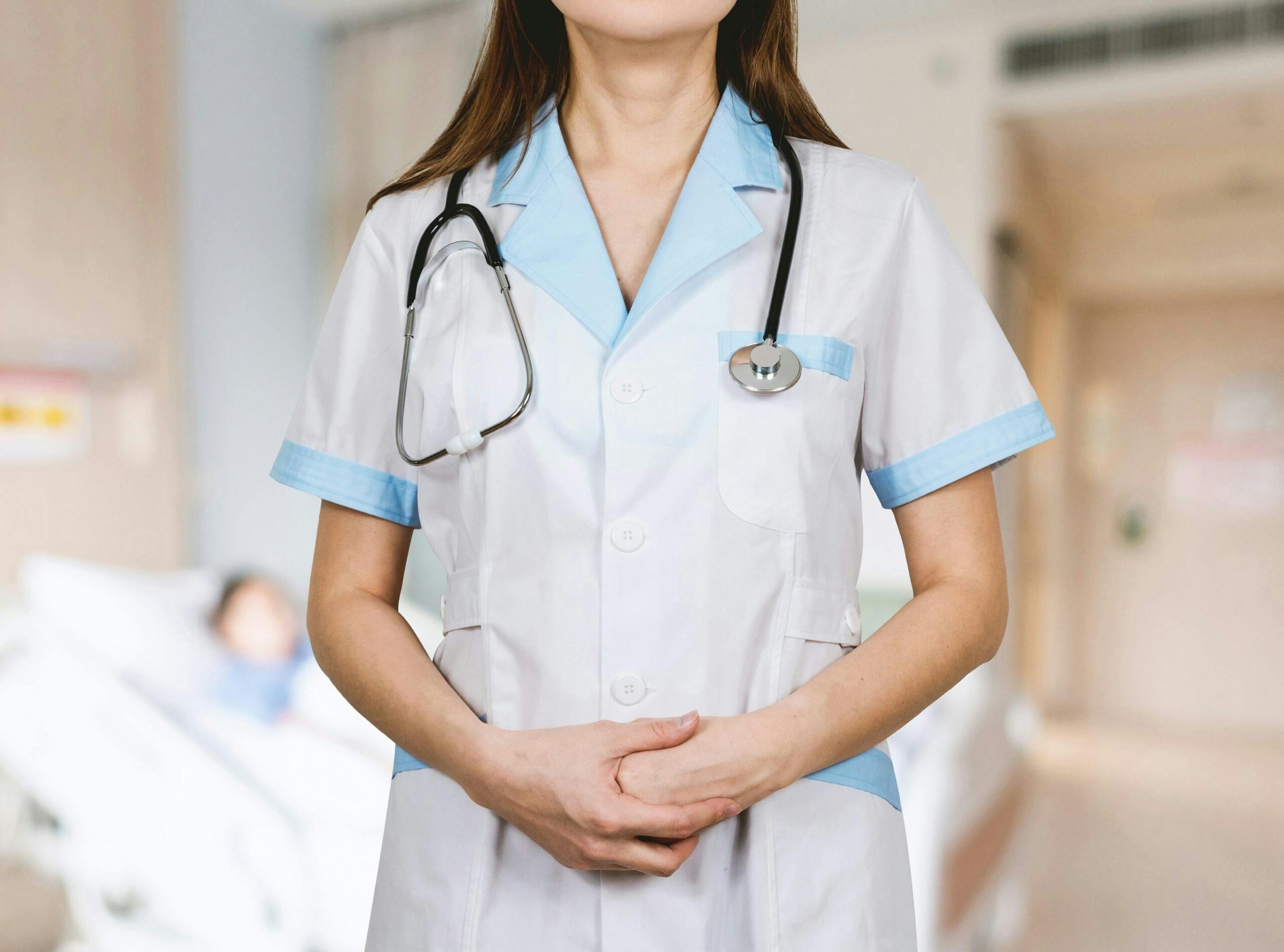 A nurse with her hands clasped in front of her.