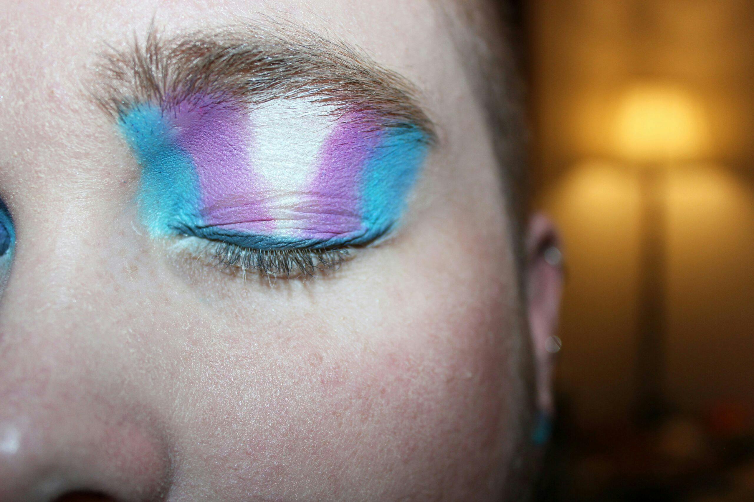 A person wearing eyeshadow in the colours of the transgender flag.