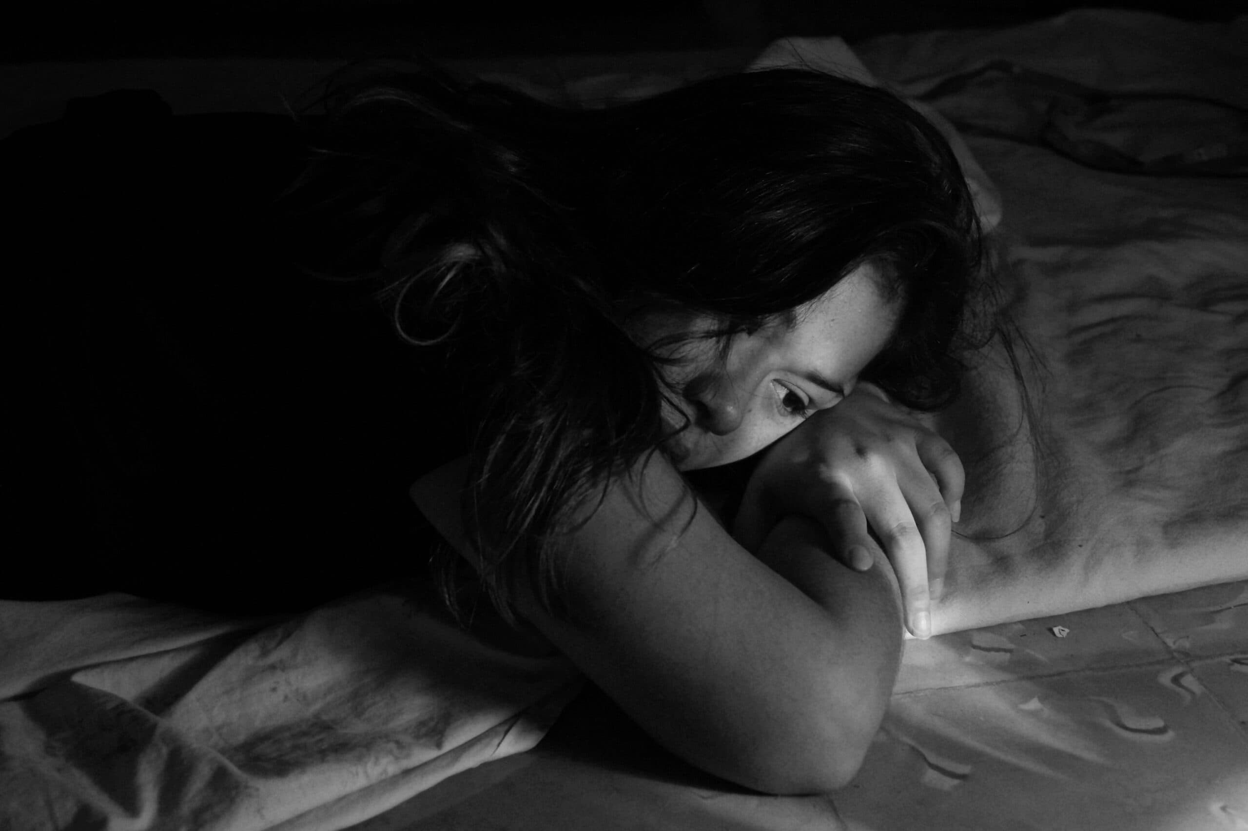 A young person lying on the floor, looking pensive.